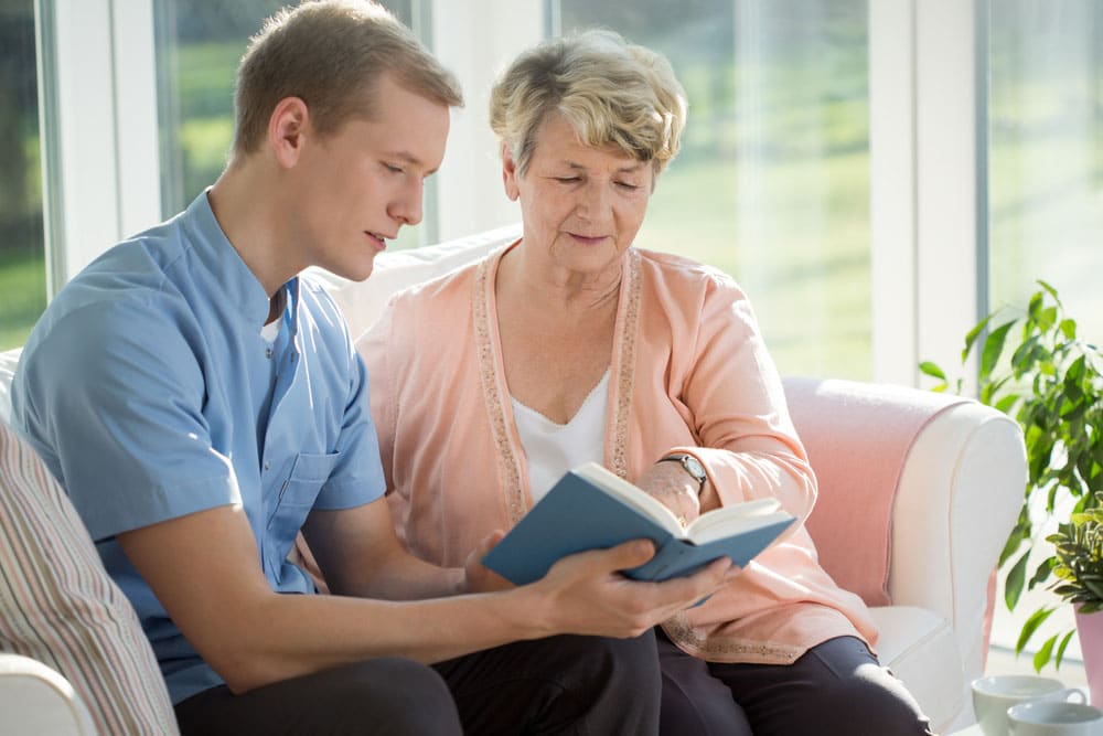 Male caregiver reading a book to his patient